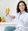 smiling-woman-holds-orange-juice-glass-in-office-2026-01-08-23-11-38-utc